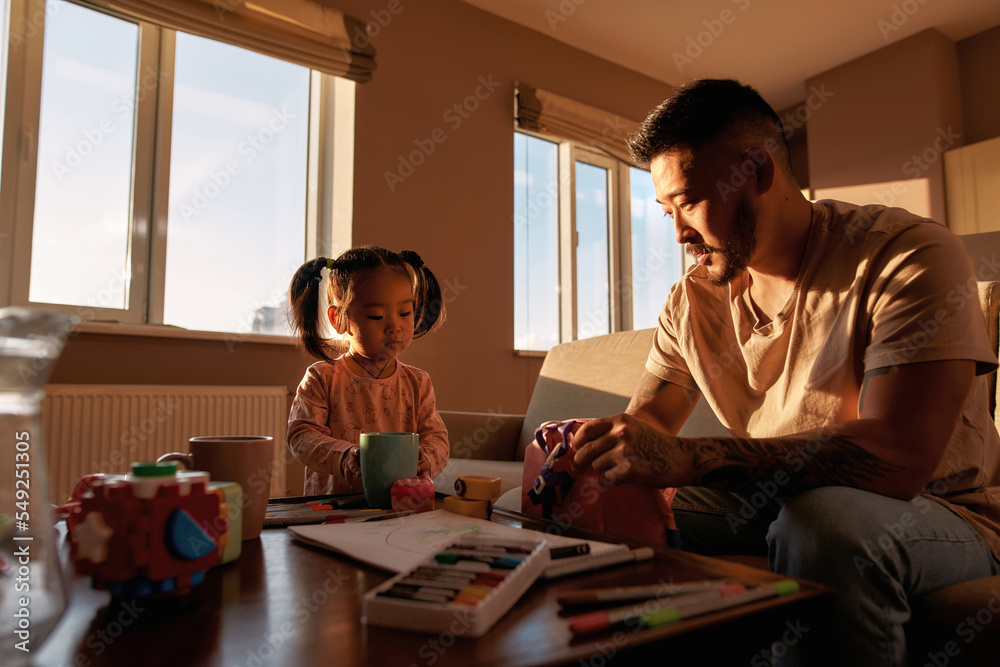 Father looking at daughter playing with cup Father looking at daughter playing with cup