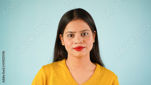 A close-up headshot portrait of a young  beautiful  confident and attractive Indian Asian woman isolated against blue background  looking at the camera