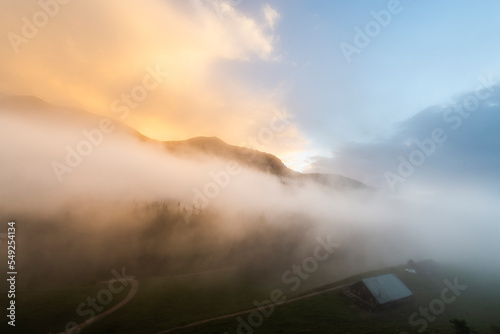 Nebelschwaden ziehen unter einem aufklarenden Himmel nach einem Sommergewitter über die Ackernalm, Tirol, Österreich
