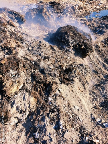 Garbage heap burnt waste pile on fire trash smoke rubbish burning ashes air pollution dump litter dirty garbage-pile solid rubbish scrap refuse waste-material debris household-waste environment photo  photo