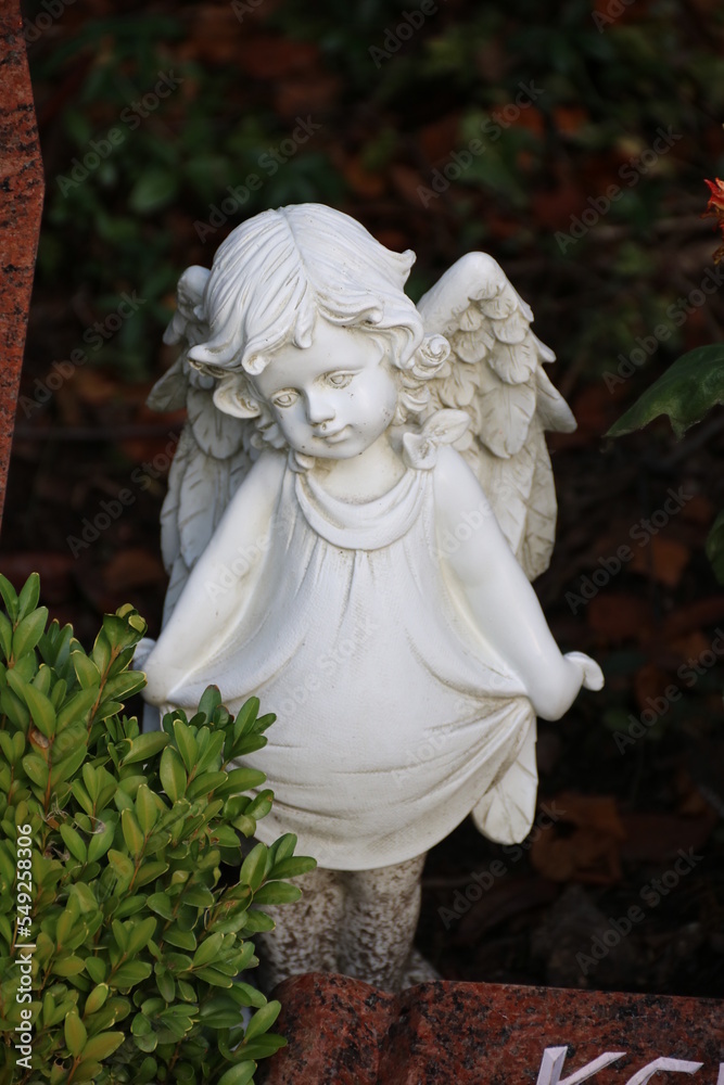 Kleiner Engel auf dem Friedhof schmückt ein Grab im Herbst Kleiner Engel auf dem Friedhof schmückt ein Grab im Herbst