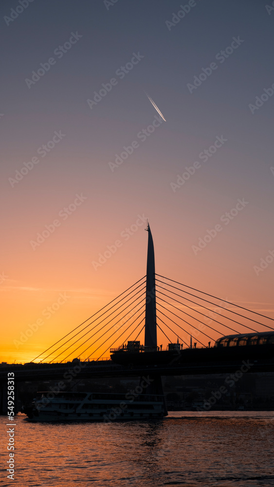 Fototapeta premium Beautiful sunset, Golden hours, Golden Horn metro bridge and the view of the Golden Horn in Istanbul, the sunset, the birds heading towards the sun, The image with space and text area.