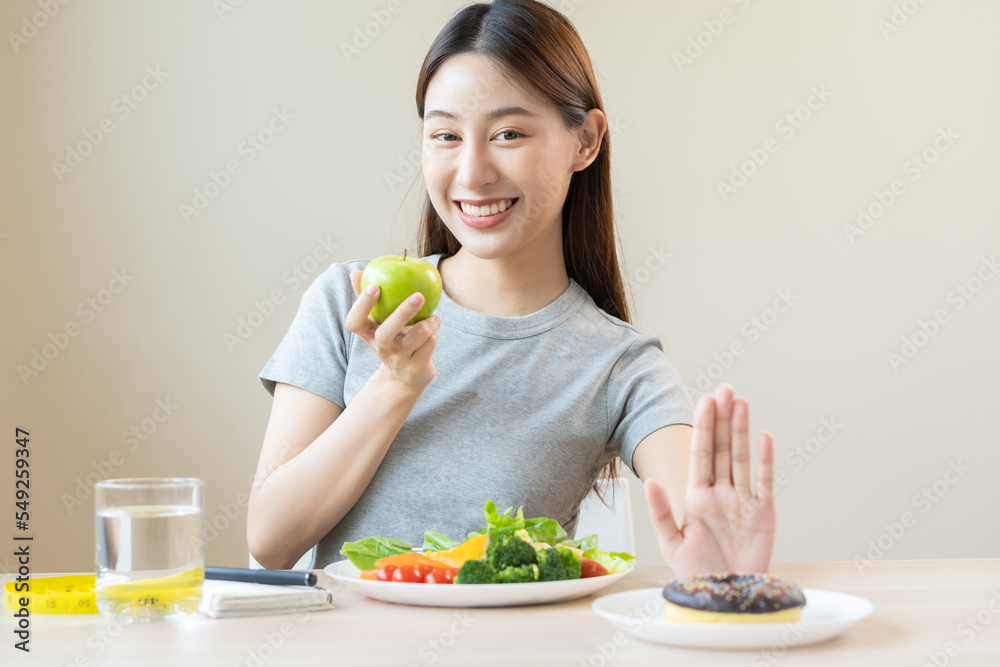 Diet, Dieting asian young woman or girl use hand push out, deny sweet donut and choose green salad vegetables, eat food for good healthy, health when hungry. Close up female weight loss person. Diet, Dieting asian young woman or girl use hand push out, deny sweet donut and choose green salad vegetables, eat food for good healthy, health when hungry. Close up female weight loss person.
