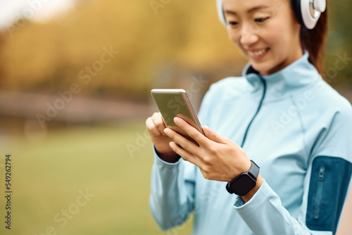 Close up of athletic woman using smart phone in park.