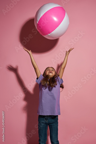 Little girl throwing beach ball and looking up © Svitlana