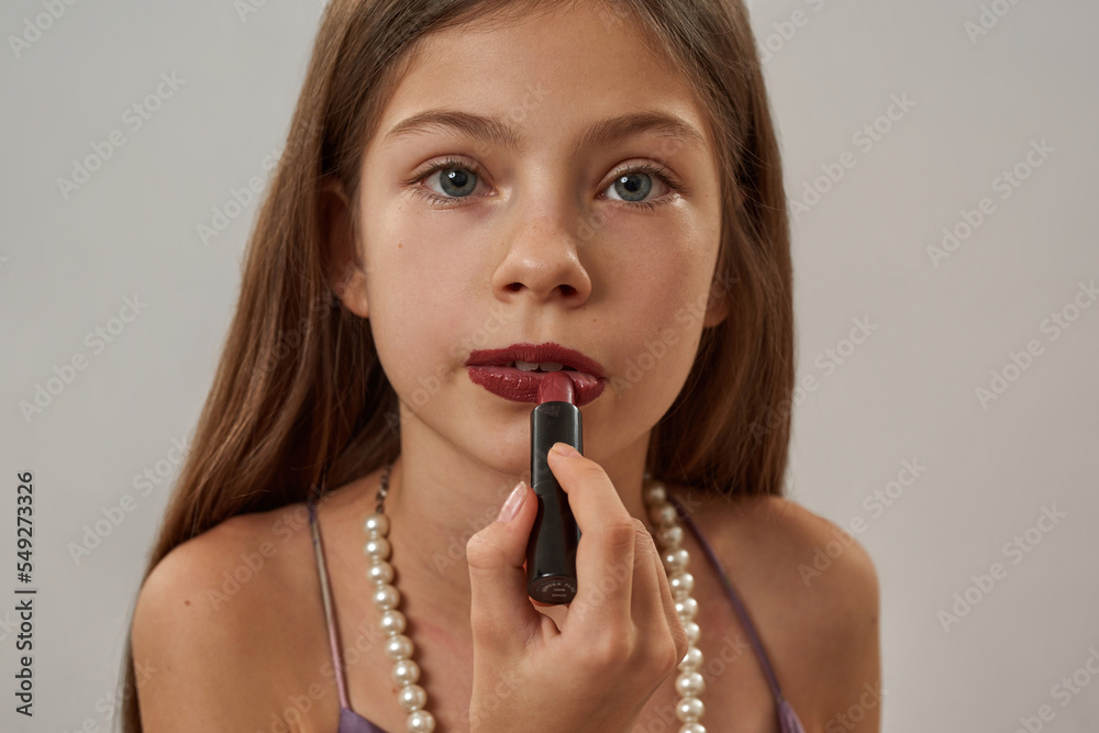 Cropped little girl painting lips with pomade Cropped little girl painting lips with pomade