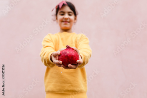 hands of child holding bright red pomegranate photo