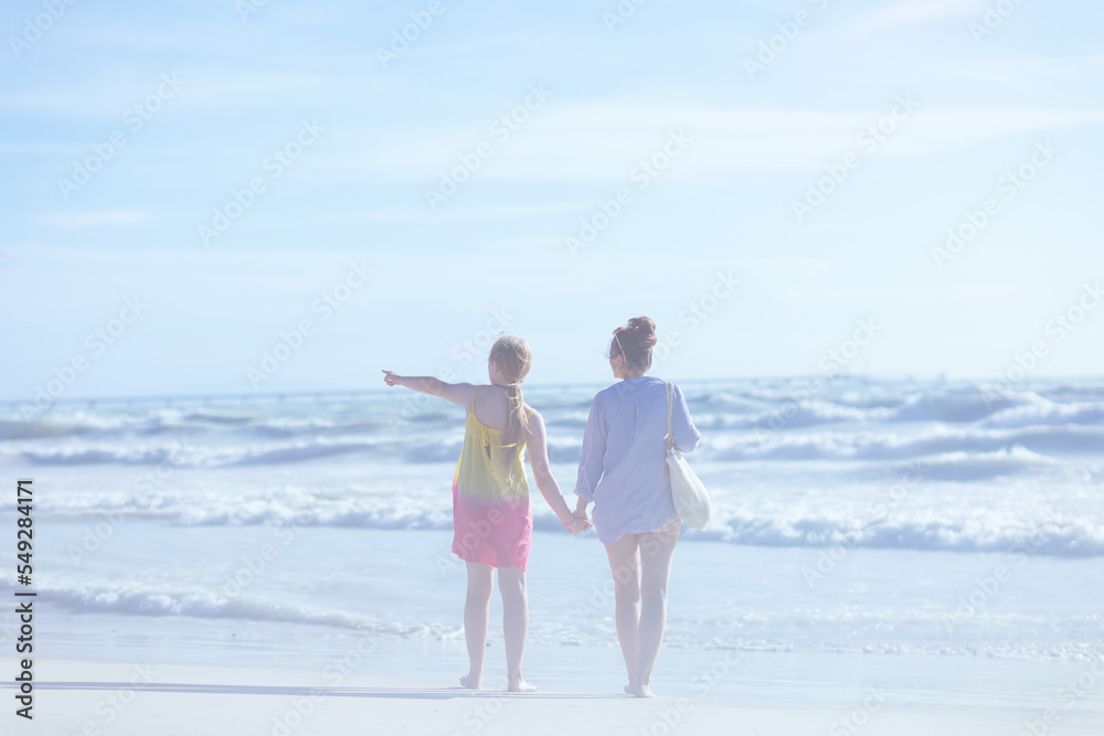 Seen from behind mother and child at beach looking into distance Seen from behind mother and child at beach looking into distance