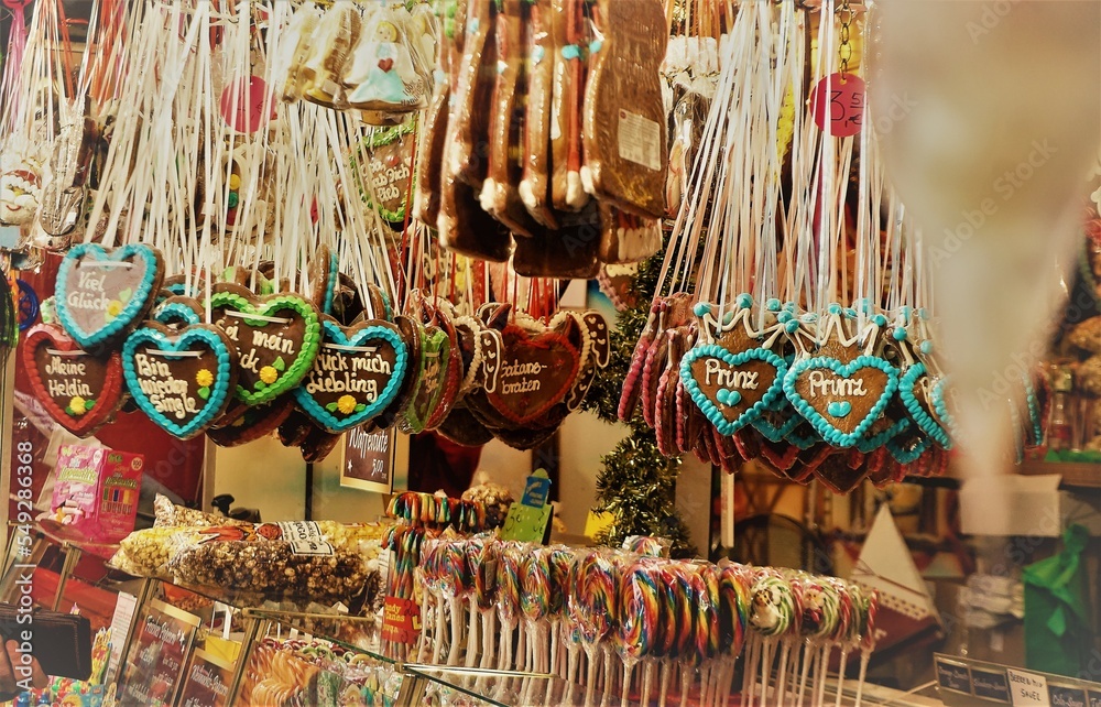 Fototapeta premium Weihnachtsmarktstand mit hängenden bunten Lebkuchenherzen und Süßigkeiten am Nachmittag im Winter