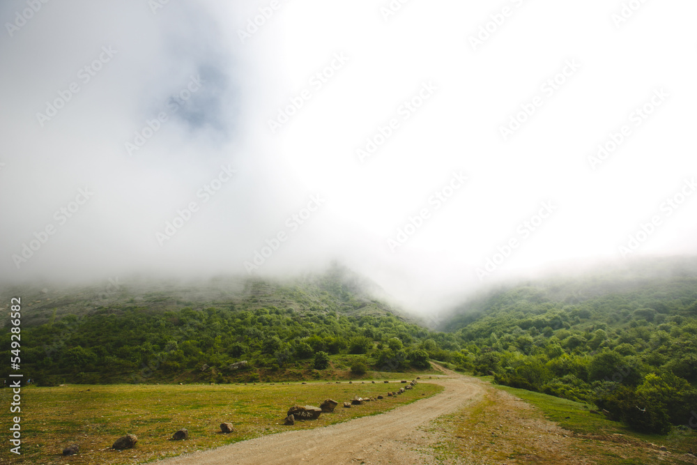 The mountains were covered with thick fog. Country road in the mountains The mountains were covered with thick fog. Country road in the mountains