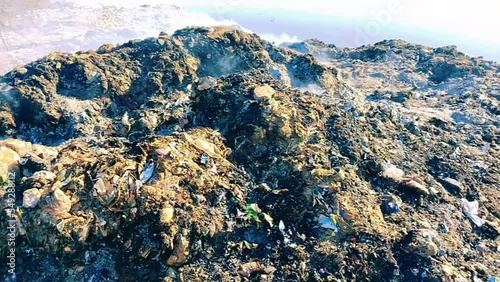 Garbage heap burnt waste pile on fire trash smoke rubbish burning ashes air pollution dump litter dirty garbage-pile solid rubbish scrap refuse waste-material debris household-waste environment video  photo
