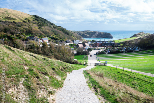 Stone road to Durdle door in Lulworth, part of Jurassic Coast World Heritage Site, view of the seaside cottages and Lulworth Cove in the background, selective focus