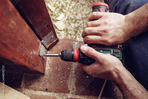 Bilde på lerret Handyman screwing a door hinge in the wooden door frame