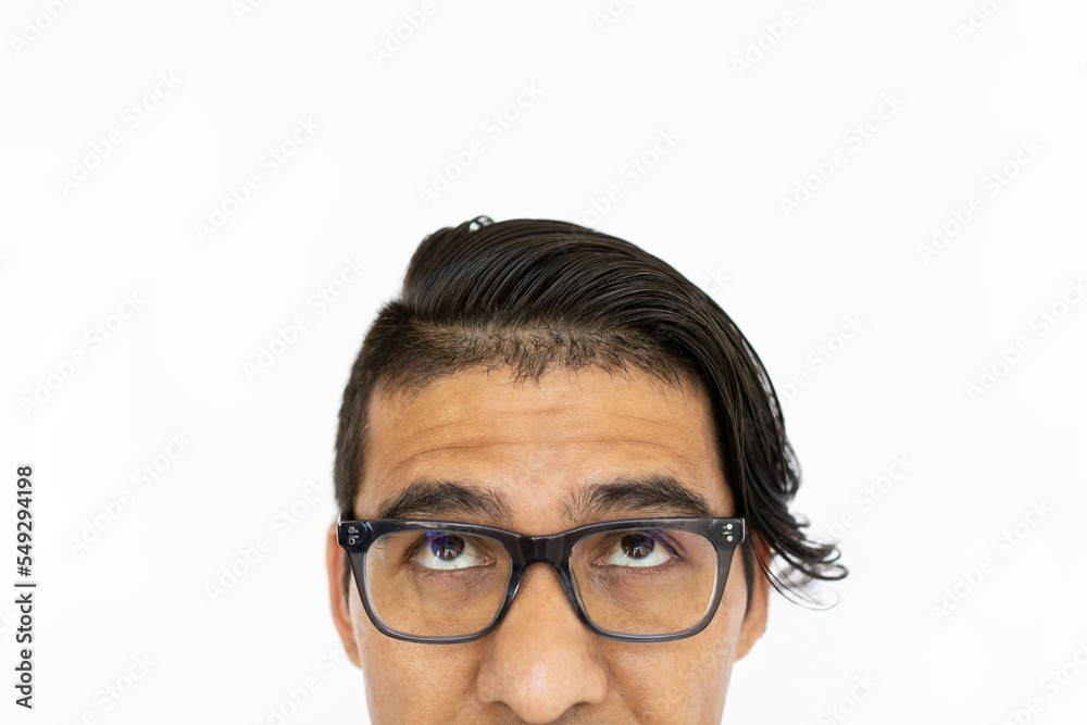 Fototapeta premium Thoughtful man looking up. Indian man in glasses thinking or dreaming. Portrait, studio shot, dreaming, thoughtfulness concept