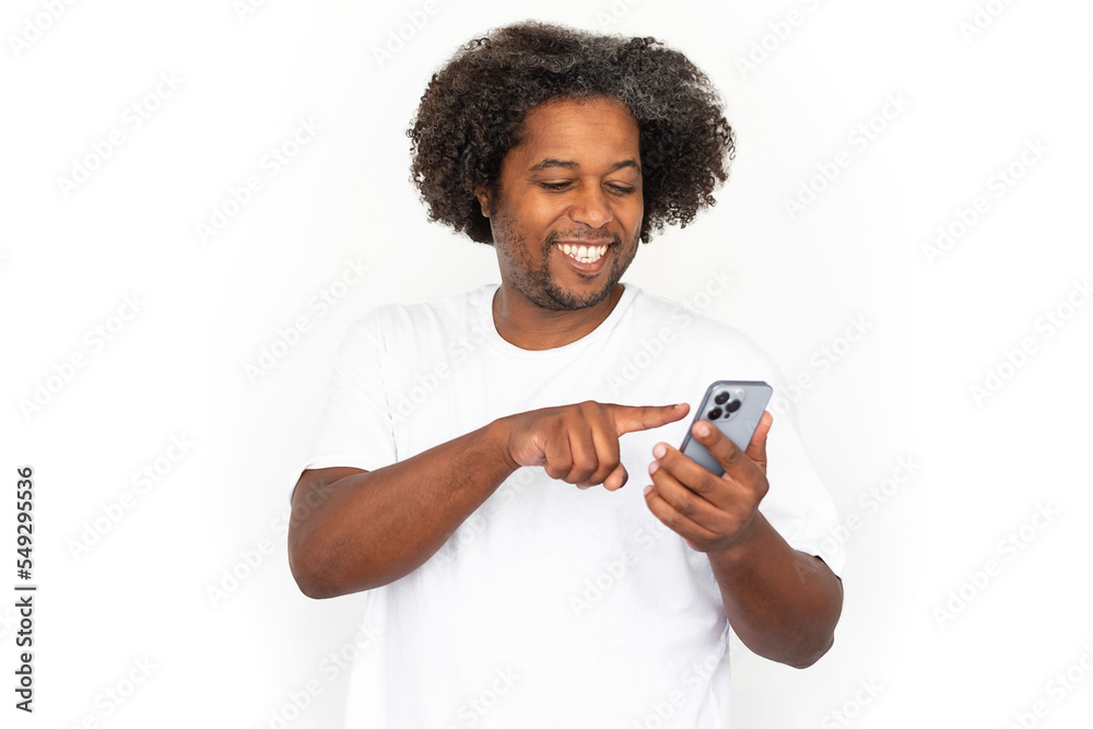 Cheerful African American man dialing ads number. Happy mature male model with dark curly hair in white T-shirt looking at screen, using phone. Modern technology, advertising concept Cheerful African American man dialing ads number. Happy mature male model with dark curly hair in white T-shirt looking at screen, using phone. Modern technology, advertising concept