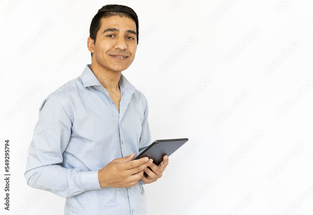 Smiling man holding tablet. Indian man in blue shirt standing with tablet. Portrait, studio shot, technology, advertising concept Smiling man holding tablet. Indian man in blue shirt standing with tablet. Portrait, studio shot, technology, advertising concept