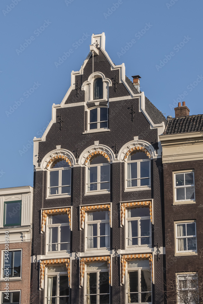 Close-up colorful old buildings with gable rooftops and hooks along Keizersgracht canal in Amsterdam. Keizersgracht (Emperor’s Canal, 1612) named after Emperor of Austria. Amsterdam, the Netherlands.