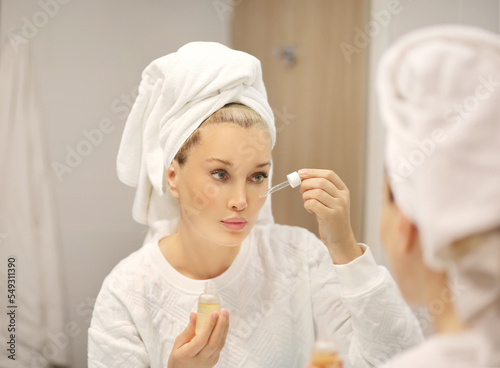 Woman looking in the mirror Applying the cream..Magic anti-aging cream...