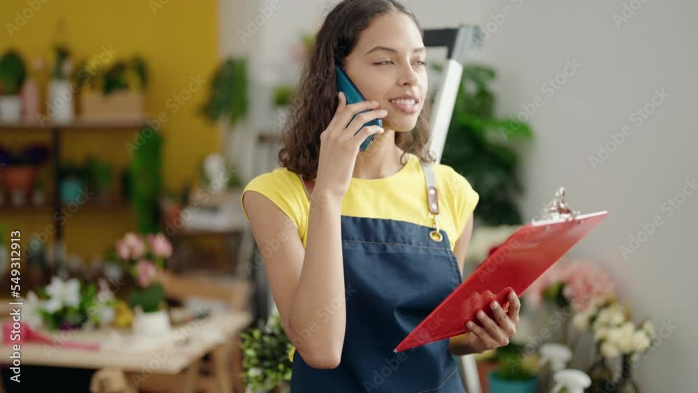 Young african american woman florist talking on smartphone reading document at flower shop Young african american woman florist talking on smartphone reading document at flower shop