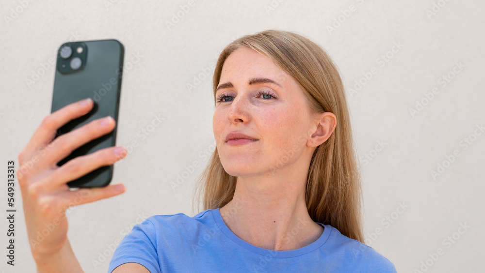Close-up of charming young woman taking selfie. Caucasian female model with blonde hair and blue eyes in casual clothes smiling and taking photo of herself. Social media, advertisement concept Close-up of charming young woman taking selfie. Caucasian female model with blonde hair and blue eyes in casual clothes smiling and taking photo of herself. Social media, advertisement concept