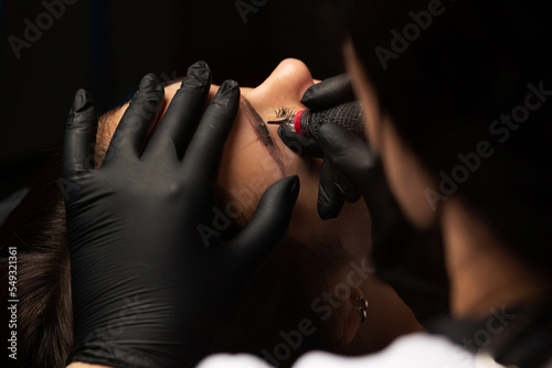 Beauty master applying permanent makeup photo