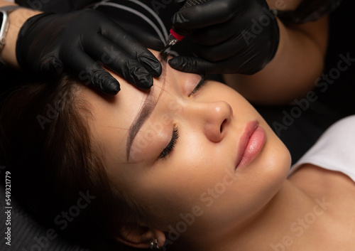 Tattoo master applying permanent makeup to a woman