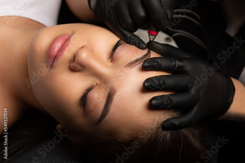 Beauty master making permanent makeup with a machine