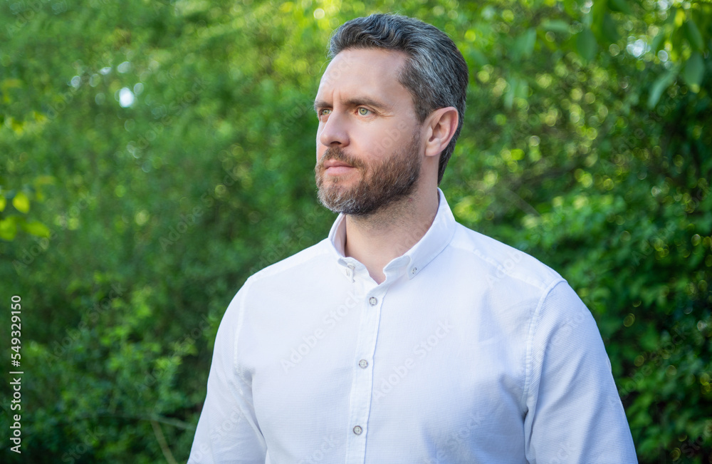 Handsome professional manger in white shirt looking aside natural background Handsome professional manger in white shirt looking aside natural background