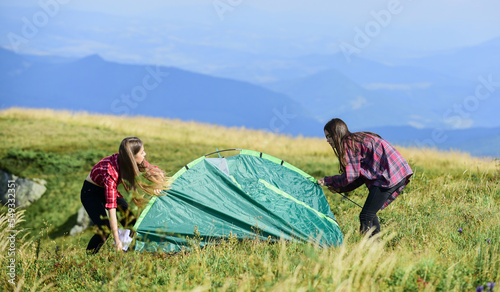 Camping trip. Helpful to have partner for raising tent. Camping skills concept. Camping and hiking. In middle of nowhere. Girls set up tent on top mountain. Temporary housing. Vacation in mountains