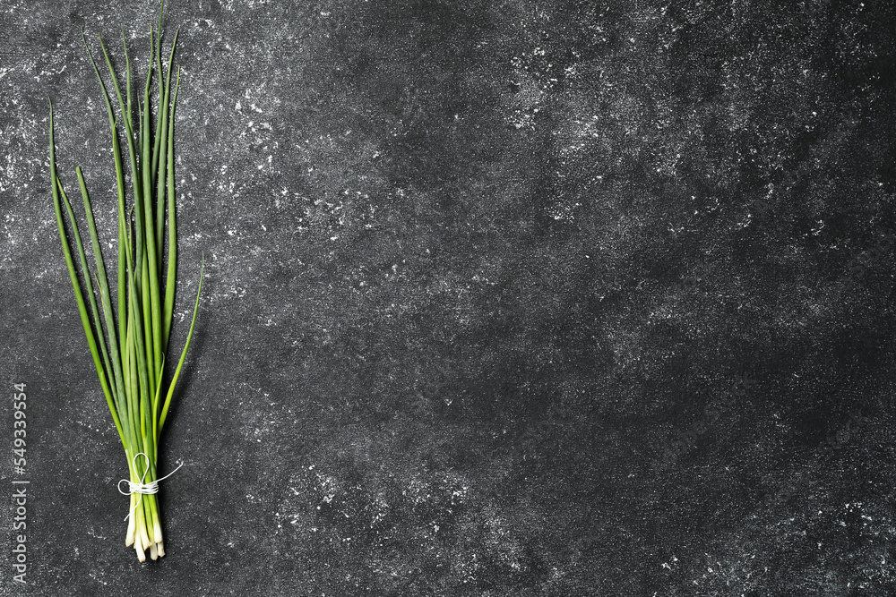 Bunch of fresh green onion on black table, top view. Space for text - obrazy, fototapety, plakaty 