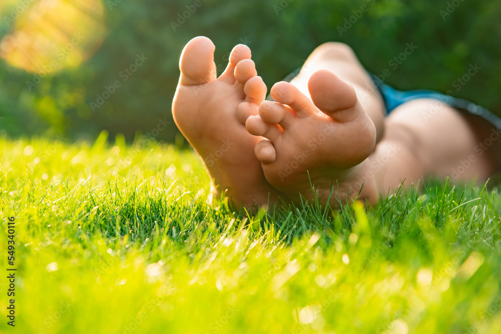 Teenage girl lying barefoot on green grass outdoors, closeup Teenage girl lying barefoot on green grass outdoors, closeup
