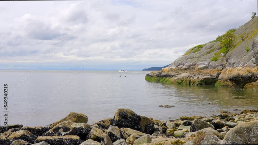 Establishing aerial shot of ocean beach with rocks and pebbles in slow motion at summer day in Vancouver, Canada, North America. Day time on September 2022. Drone forward. ProRes 422 HQ. Establishing aerial shot of ocean beach with rocks and pebbles in slow motion at summer day in Vancouver, Canada, North America. Day time on September 2022. Drone forward. ProRes 422 HQ.