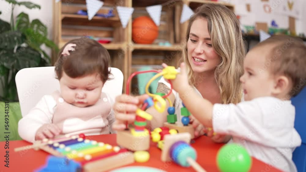 Teacher and preschool students playing with toys sitting on table at kindergarten