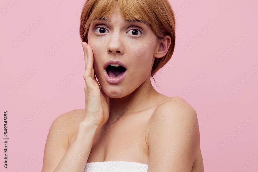 a close horizontal beauty photo on a pink background of a surprised woman with her hair pinned up from behind, looking into the camera with her mouth wide open, holding her hand near her face a close horizontal beauty photo on a pink background of a surprised woman with her hair pinned up from behind, looking into the camera with her mouth wide open, holding her hand near her face