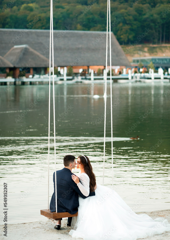 A couple in love is swinging on a swing against the background of a lake