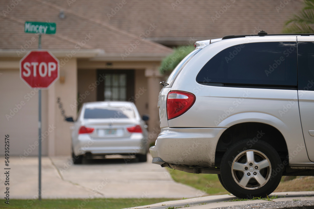 Car parked in front of wide garage double door on concrete driveway of new modern american house Car parked in front of wide garage double door on concrete driveway of new modern american house