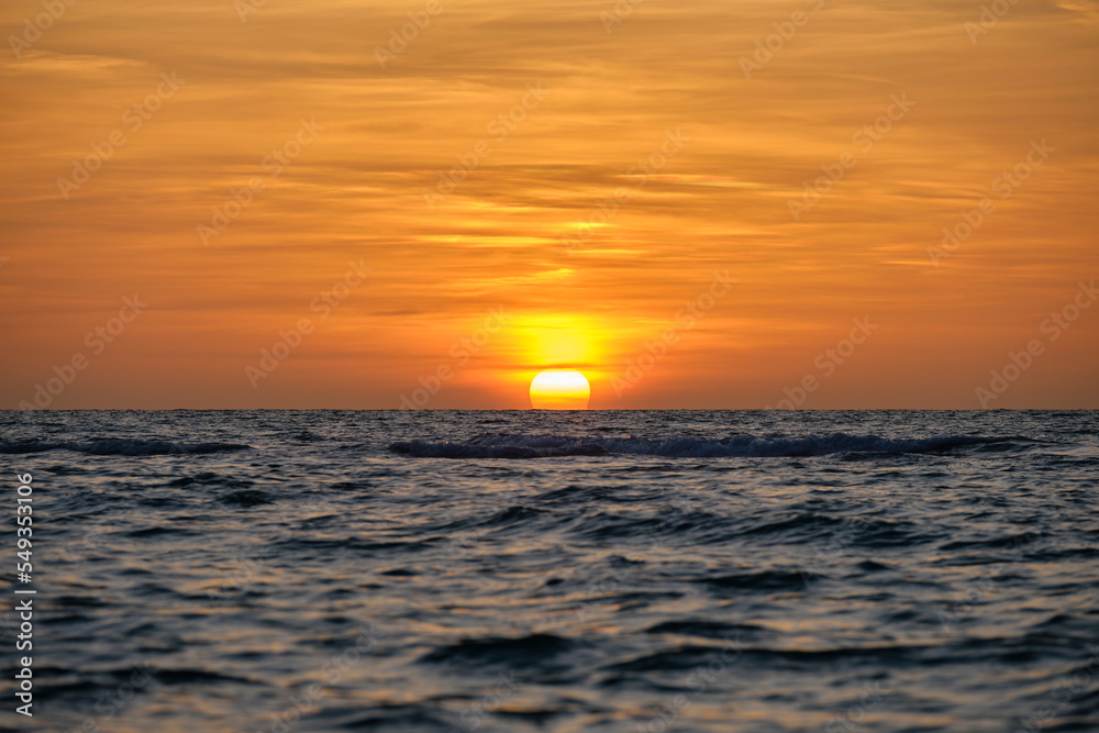 Ocean sunset. Big white sun on dramatic bright sky background, soft evening horizont over sea dark water