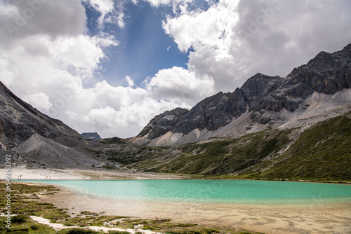 Panorama of unique colored Milk lake  approx. 4300m altitude  with blue sky and sharp mountains around it in Daocheng Yading Nature Reserve  Sichuan  China.