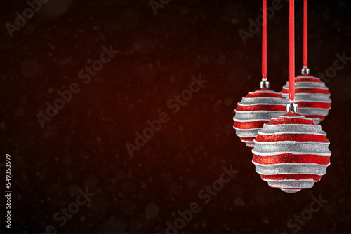 Red Christmas tree ornaments hanging with copy space. Christmas Balls made of glass or plastic hanging over abstract dark red background. photo