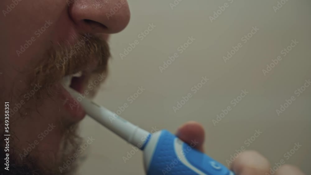 Man brushes his teeth with an electric toothbrush. Daily routine