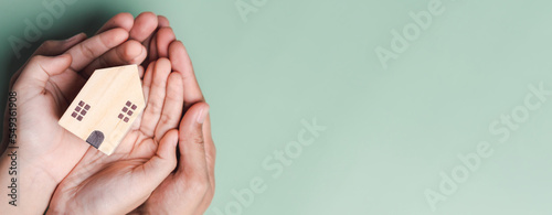 hands holding wooden house, family home, homeless housing, mortgage crisis and home protecting insurance, international day of families, foster home care, family day care, stay home concept