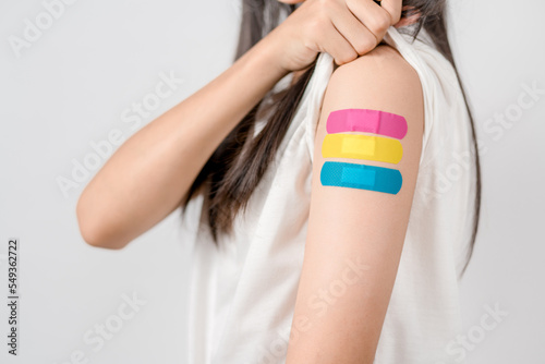 Happy young woman after getting a vaccine. showing shoulder arm with bandage after receiving vaccination, herd immunity, side effect, booster dose, vaccine passport and Coronavirus pandemic