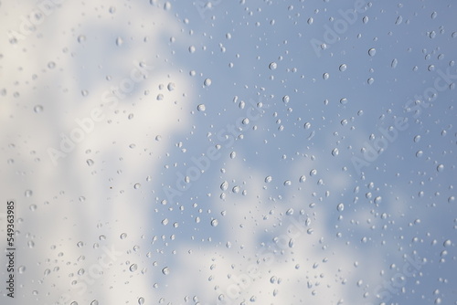 창문에 맺힌 빗방울 너머로 보이는 파란 하늘과 구름