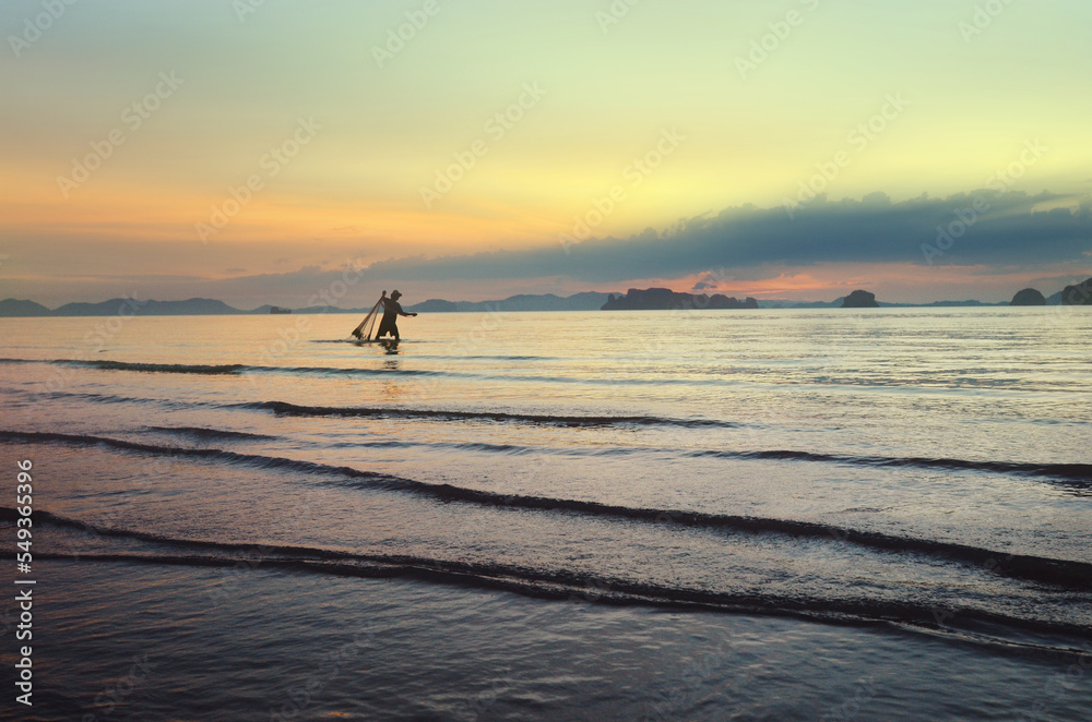 Fisherman at sunset fishing. Traditional Thai fishing. Thailand. Province Of Krabi. Beautiful view of an exotic Thai beach and Bay at low tide. Beautiful relaxing natural background