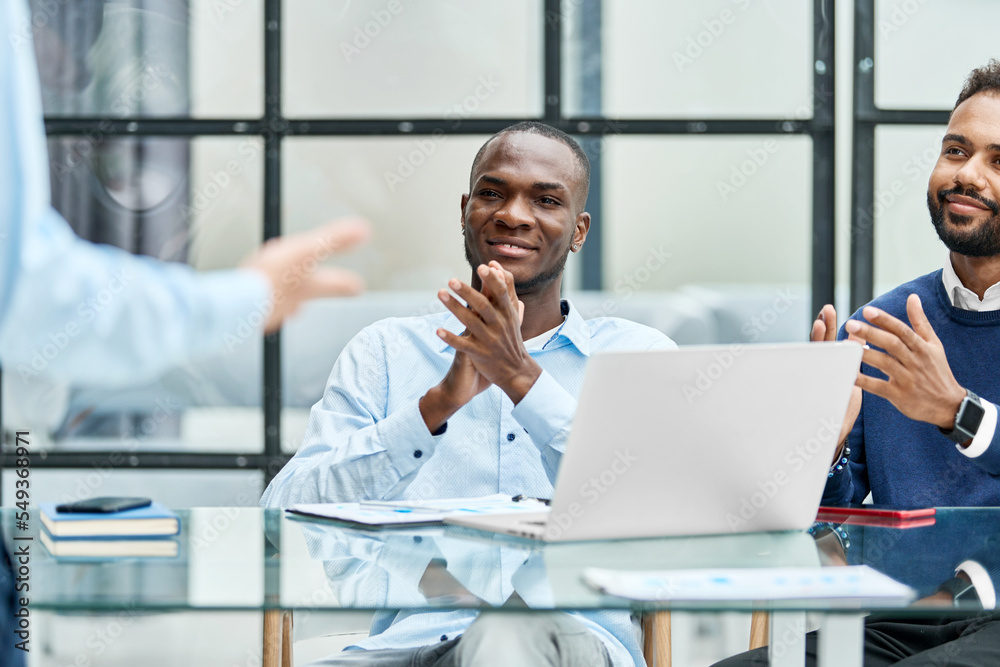 business team applauding their colleague sitting at the desk. business team applauding their colleague sitting at the desk.