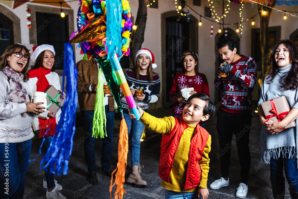 Hispanic child boy with Mexican family breaking a pinata at traditional  posada party for Christmas in Mexico Latin America Stock Photo