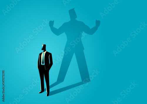 Businessman standing and casting a shadow of a strong superhero photo