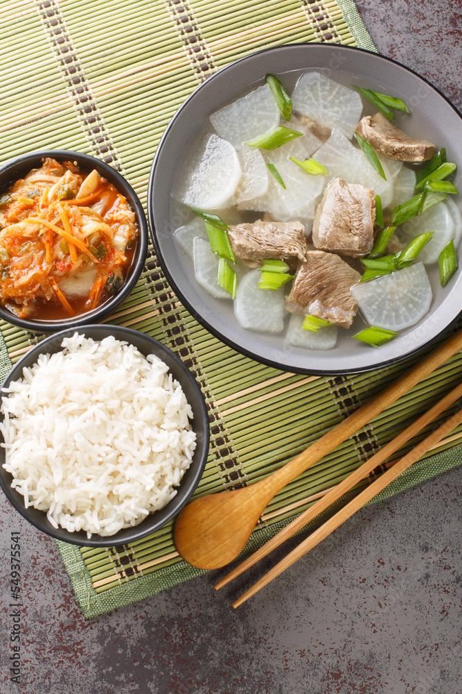 Korean Beef Radish Soup Sogogi Muguk served with rice and kimchi closeup on the mat on the table. Vertical top view from above Korean Beef Radish Soup Sogogi Muguk served with rice and kimchi closeup on the mat on the table. Vertical top view from above