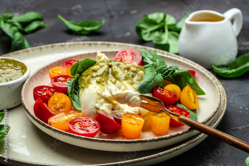 Traditional Italian dish burrata cheese with glass of rose wine. Burrata served with tomatoes and green pesto. place for text, top view