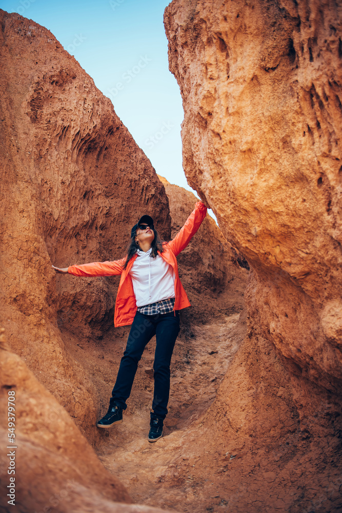 Young happy woman tourist standing in red canyon. Brave female hiker in solo trekking. Adventure, wanderlust, sightseeing. Vertical image. Young happy woman tourist standing in red canyon. Brave female hiker in solo trekking. Adventure, wanderlust, sightseeing. Vertical image.